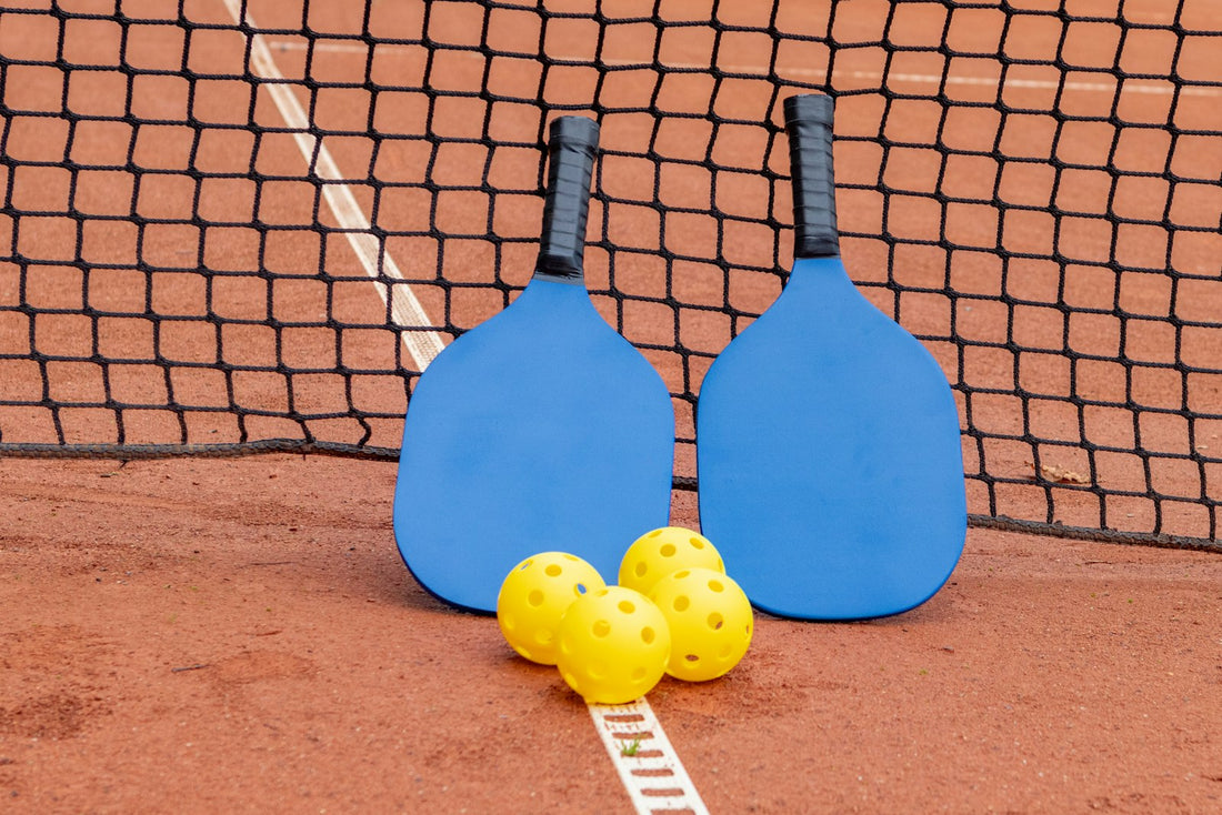 Pickleball paddles and balls resting on a court