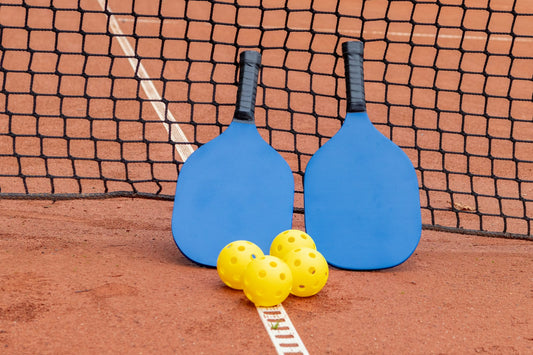 Pickleball paddles and balls resting on a court